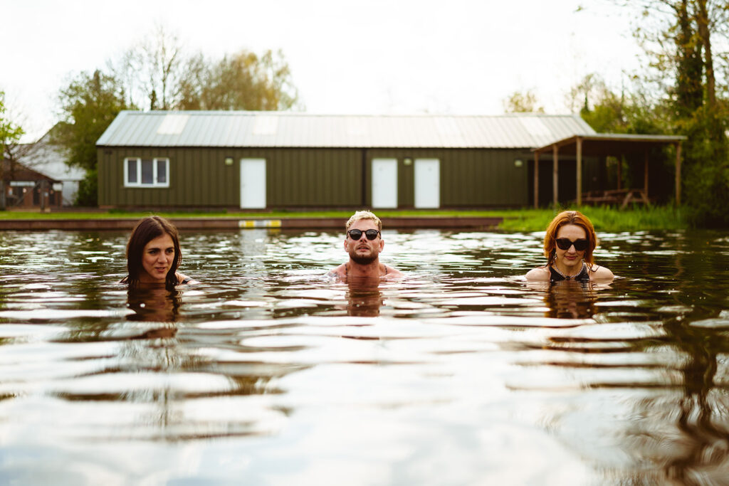 Three people doing cold water swimming in winter